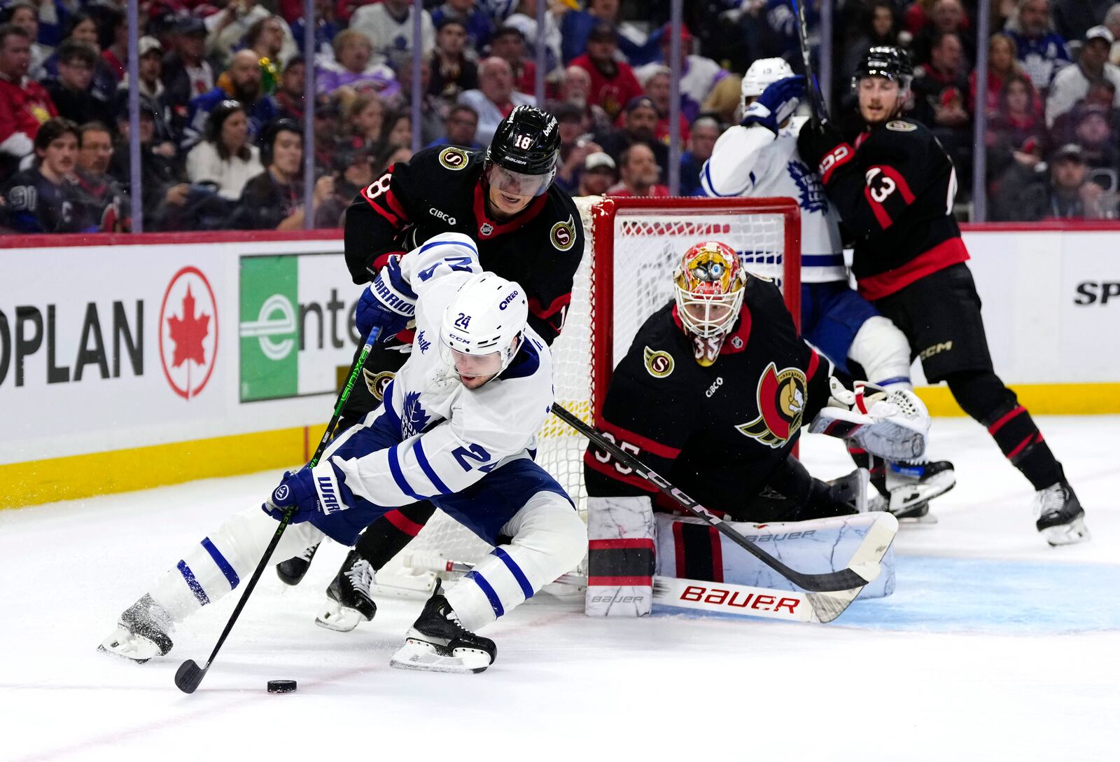 Toronto Maple Leafs' Scott Laughton (24) tries to get the puck past Ottawa Senators' Tim Stutzle (18) as goaltender Linus Ullmark (35) guards the net, during third period NHL playoff action in Ottawa, on Saturday, April 26, 2025. (Adrian Wyld/The Canadian Press via AP)
