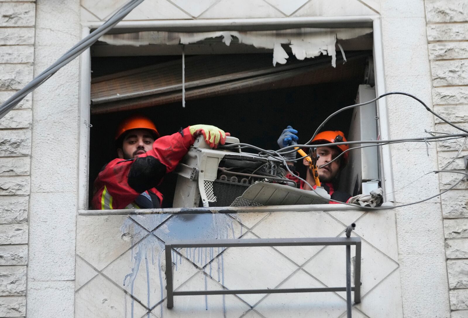 Rescue workers remove an air-condition compressor from a damaged apartment at the site of an Israeli airstrike on Dahiyeh in the southern suburb of Beirut, Lebanon, Sunday, April 27, 2025. (AP Photo/Hussein Malla)