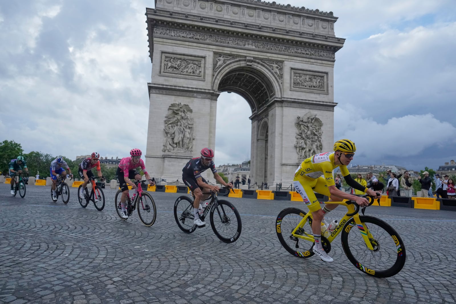 The pack with Slovenia's Tadej Pogacar, wearing the overall leader's yellow jersey, passes the Arc de Triomphe during the twenty-first stage of the Tour de France cycling race over 132.3 kilometers (82.1 miles) with start in Mantes-la-Ville and finish on the Champs-Elysees in Paris, France, Sunday, July 27, 2025. (AP Photo/Mosa'ab Elshamy)
