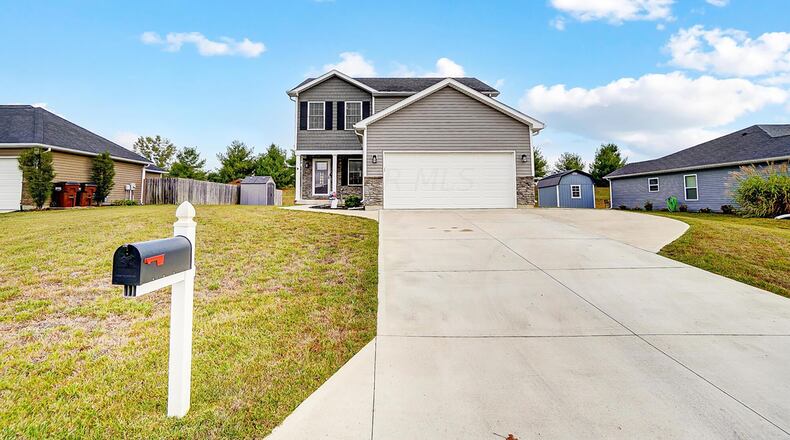 The front of the vinyl and stone two story has a concrete driveway with extension and a two car attached garage with opener.