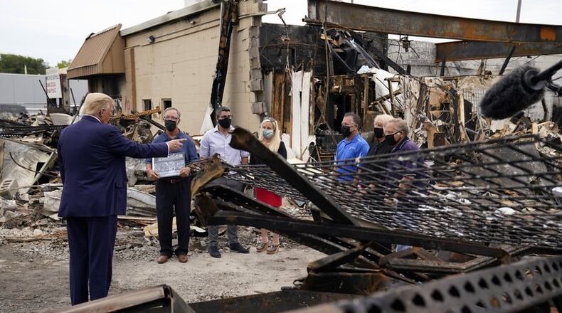 President Donald Trump talks to business owners Tuesday, Sept. 1, 2020, as he tours an area damaged during demonstrations after a police officer shot Jacob Blake in Kenosha, Wis.