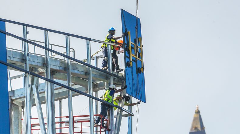 Atlanta construction workers move glass into place on the face of the rising Spring @ 8th, the new corporate headquarters for NCR Corp., in this July 2017 photo. JOHN SPINK/JSPINK@AJC.COM.