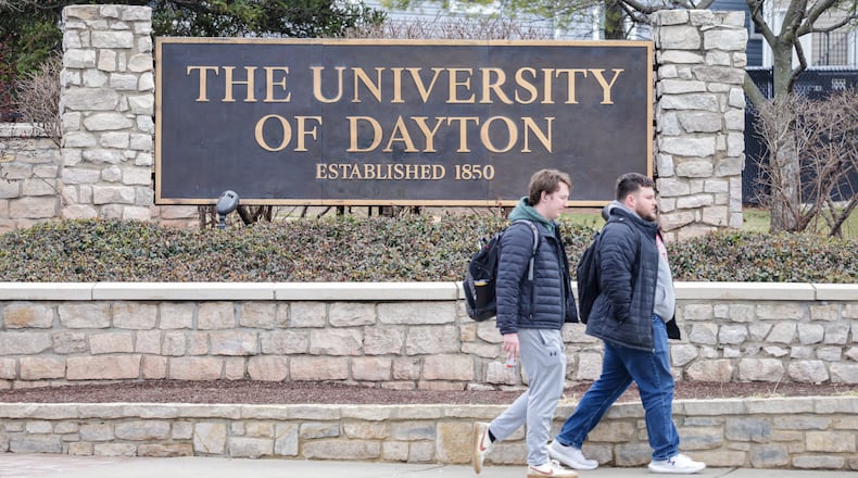 Two men walk by a University of Dayton sign on East Stewart Street on Monday, March 2. BRYANT BILLING / STAFF