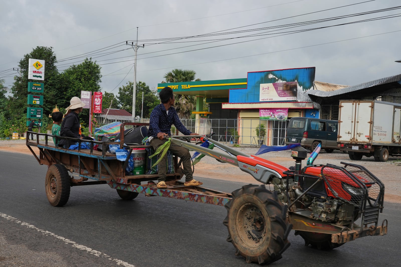 A Cambodian family returning home from a temporary shelter drive past a gas station damaged in Phrong village, Oddar Meanchey province, Cambodia, Wednesday, July 30, 2025, after a ceasefire to end deadly border clashes was reached between Thailand and Cambodia. (AP Photo/Heng Sinith)