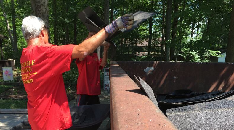 Workers with Dependable Roofing toss old shingles out. Staff Photo/Katherine Collins