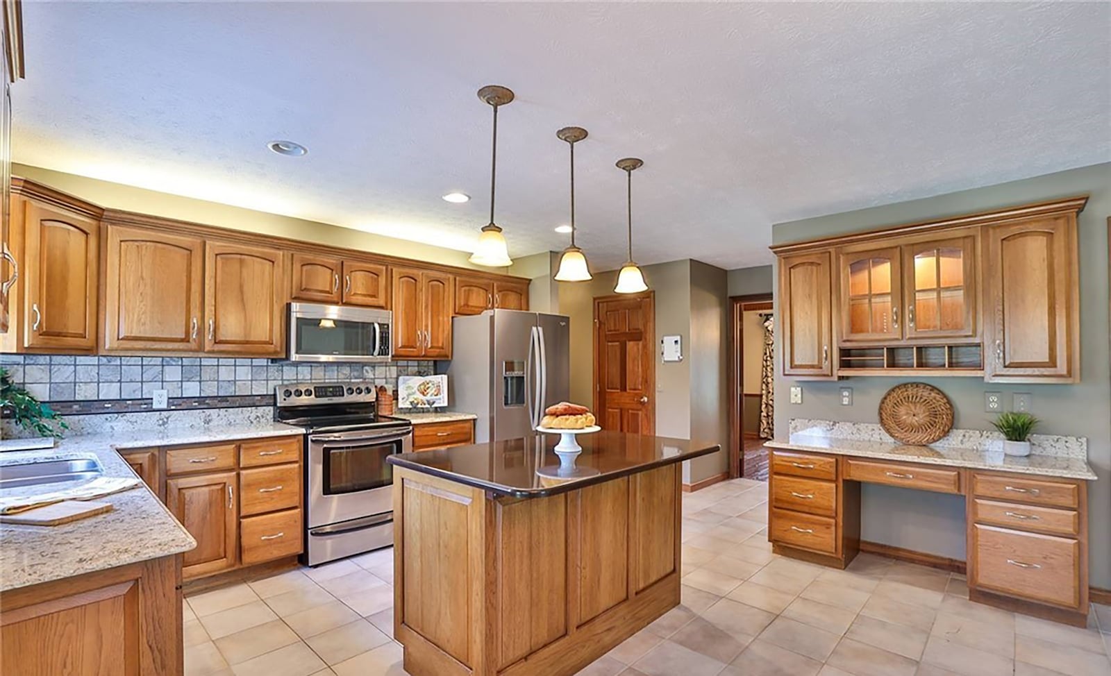 The kitchen has tile flooring, an island with bar seating, planning desk, recessed and pendant lighting and a walk in pantry. CONTRIBUTED