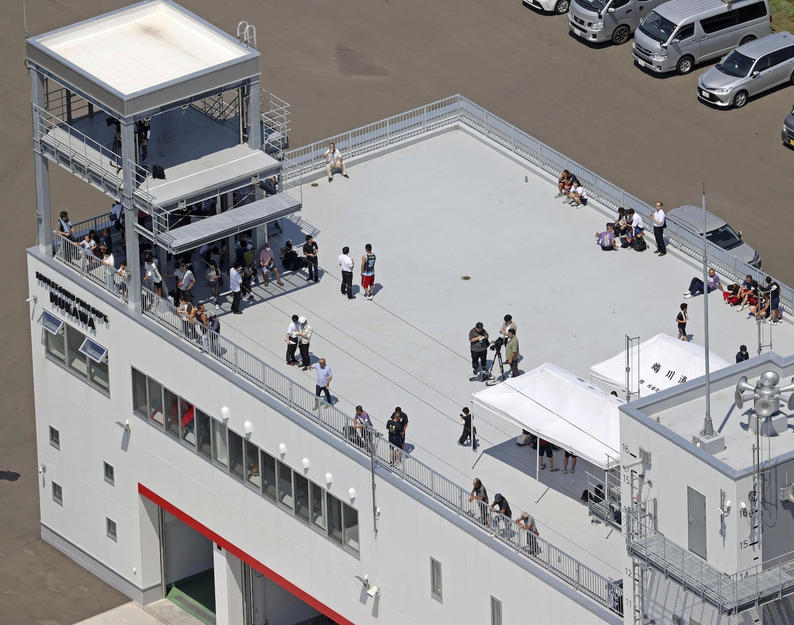 People take shelter on the roof of a fire station in Mukawa town, Hokkaido, northern Japan Wednesday, July 30, 2025, after a powerful earthquake in Russia's Far East prompted tsunami alert in parts of Japan. (Kyodo News via AP)