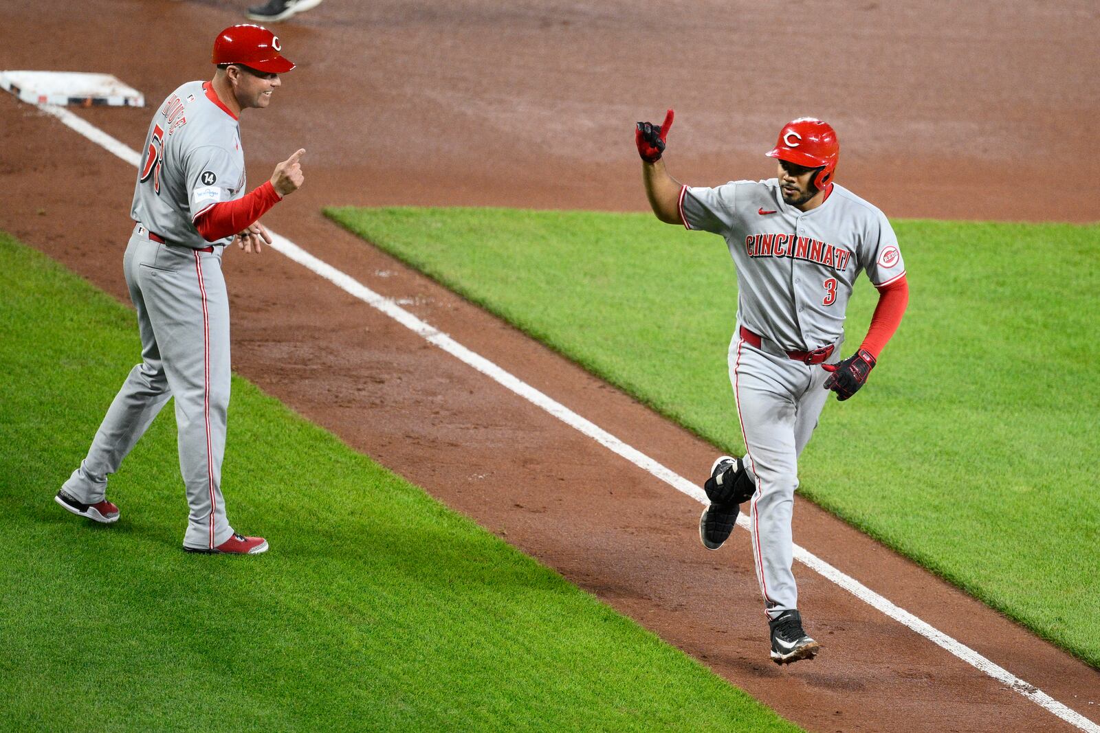 Cincinnati Reds' Jeimer Candelario (3) celebrates his home run with third base coach J.R. House, left, during the fourth inning of a baseball game against the Baltimore Orioles, Friday, April 18, 2025, in Baltimore. (AP Photo/Nick Wass)