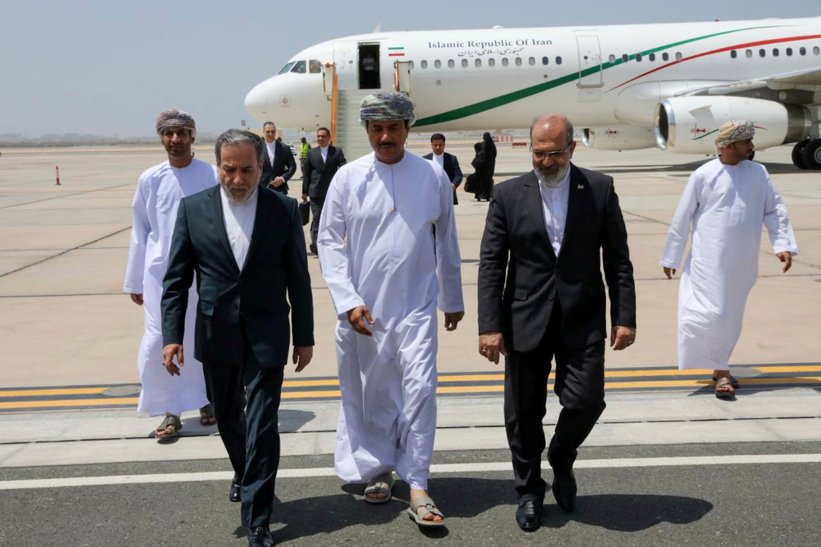 In this photo released by the Iranian Foreign Ministry, Iranian Foreign Minister Abbas Araghchi, left, is welcomed by an unidentified Omani official, center, upon his arrival at Muscat, Oman, for negotiations with U.S. Mideast envoy Steve Witkoff, as Iranian Ambassador to Oman Mousa Farhang walks at right, Sunday, May 11, 2025. (Iranian Foreign Ministry via AP)