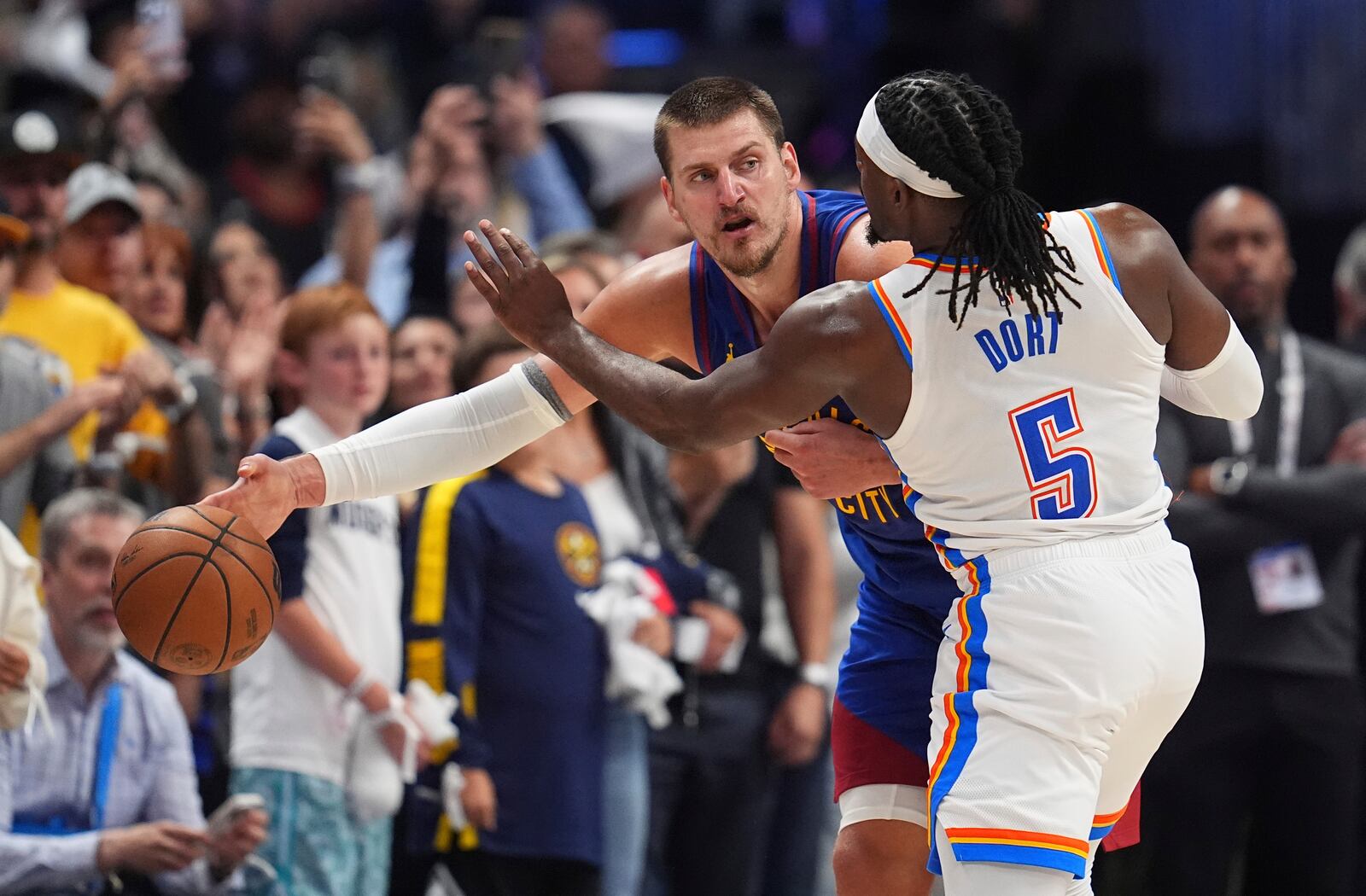 Denver Nuggets center Nikola Jokic, back, passes the ball as Oklahoma City Thunder guard Luguentz Dort defends in overtime of Game 3 in the Western Conference semifinals of the NBA basketball playoffs Friday, May 9, 2025, in Denver. (AP Photo/David Zalubowski)