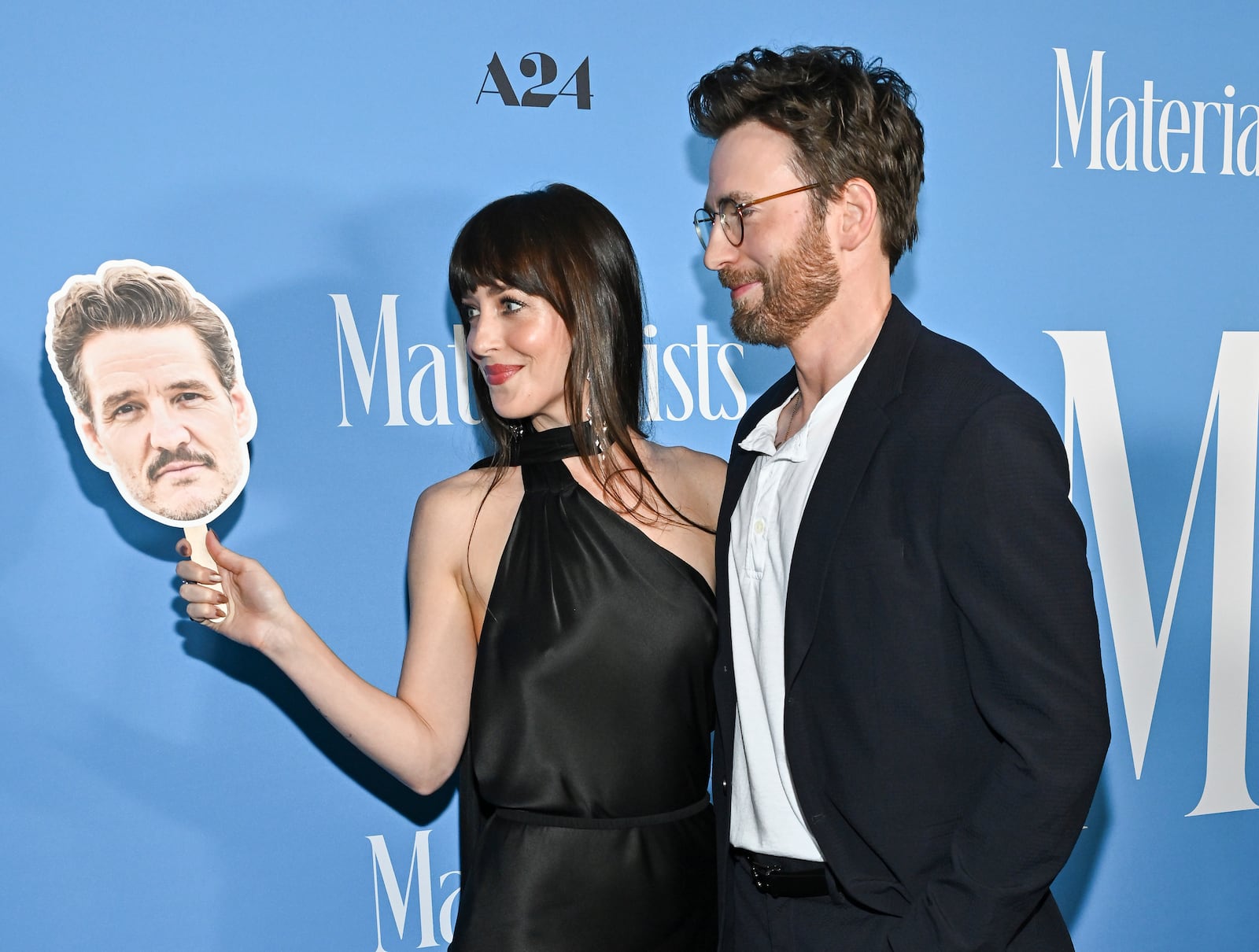 Dakota Johnson, left, and Chris Evans pose with a Pedro Pascal head cutout at the premiere of "Materialists" at the DGA New York Theater on Saturday, June 7, 2025, in New York. (Photo by Evan Agostini/Invision/AP)