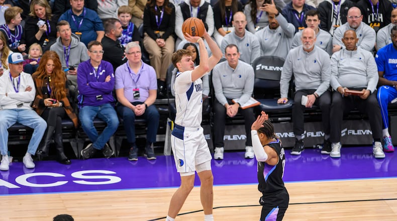 Dallas Mavericks forward Cooper Flagg, center, shoots over Utah Jazz guard Keyonte George, right, during the first half of an NBA basketball game, Monday, Dec. 15, 2025, in Salt Lake City. (AP Photo/Tyler Tate)