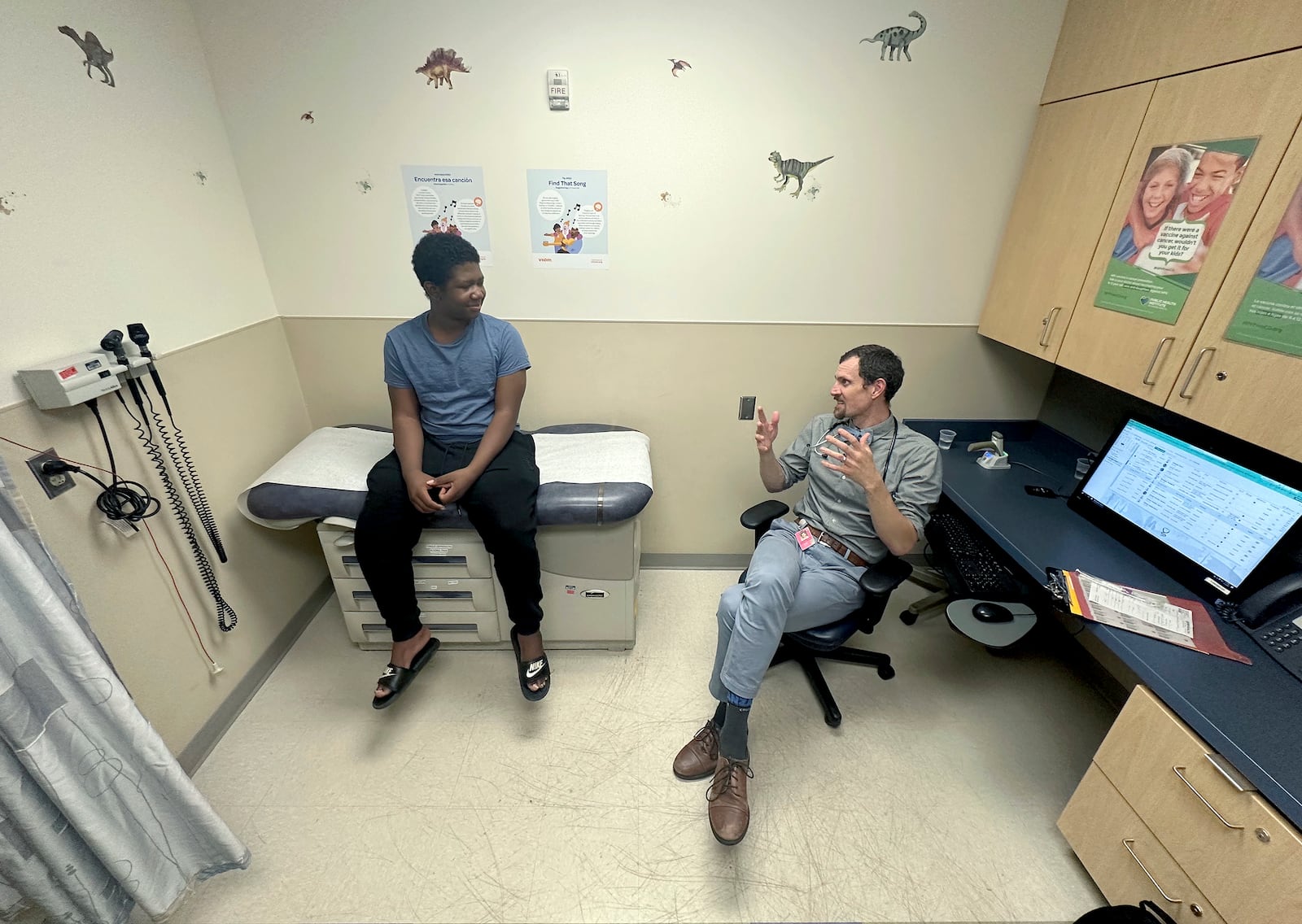 Dr. Joshua Williams, a pediatrician whose federal funding for a vaccine awareness program was cut, talks to 12-year-old patient Tiovian Darden in Denver on Tuesday, March 18, 2025. (AP Photo/Thomas Peipert)