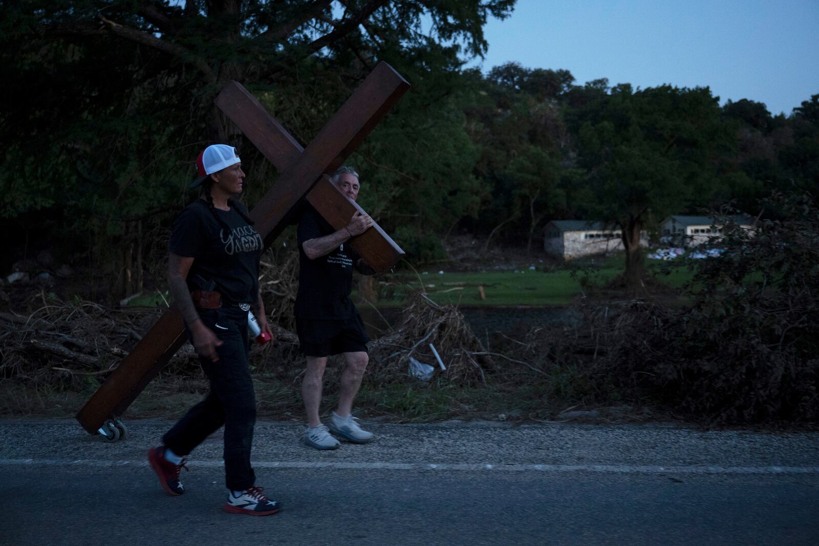 Disaster relief chaplain Sandi Gilmer, left, and Dan Beazley search for a permanent place for Beazley's large cross in memory of flooding victims on Tuesday, July 8, 2025, near Camp Mystic in Hunt, Texas, after a flash flood swept through the area. (AP Photo/Eli Hartman)