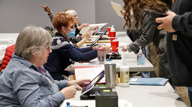 Poll workers check voters in at the First Christian Church on Middle Urbana Road Tuesday, March 19, 2024. BILL LACKEY/STAFF