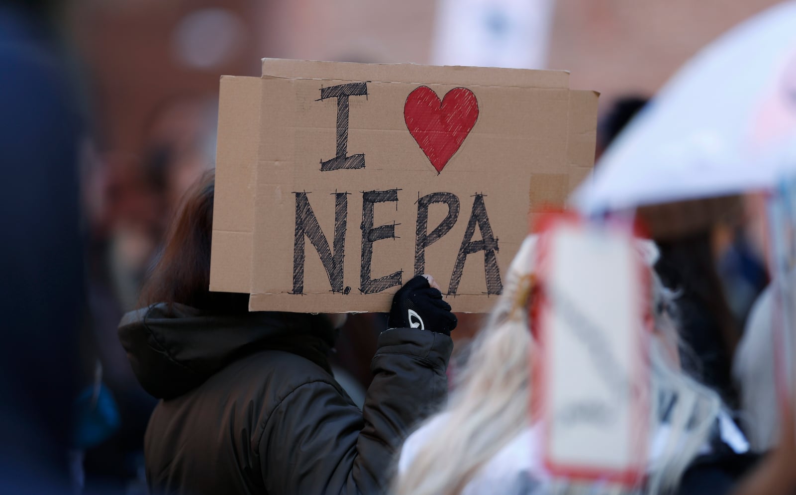 FILE - Joan Lutz, of Boulder, Colo., waves a placard at a rally of advocates to voice opposition to efforts by the Trump administration to weaken the National Environmental Policy Act, which is the country's bedrock law aimed at protecting the environment, on Feb. 11, 2020, in Denver. (AP Photo/David Zalubowski)