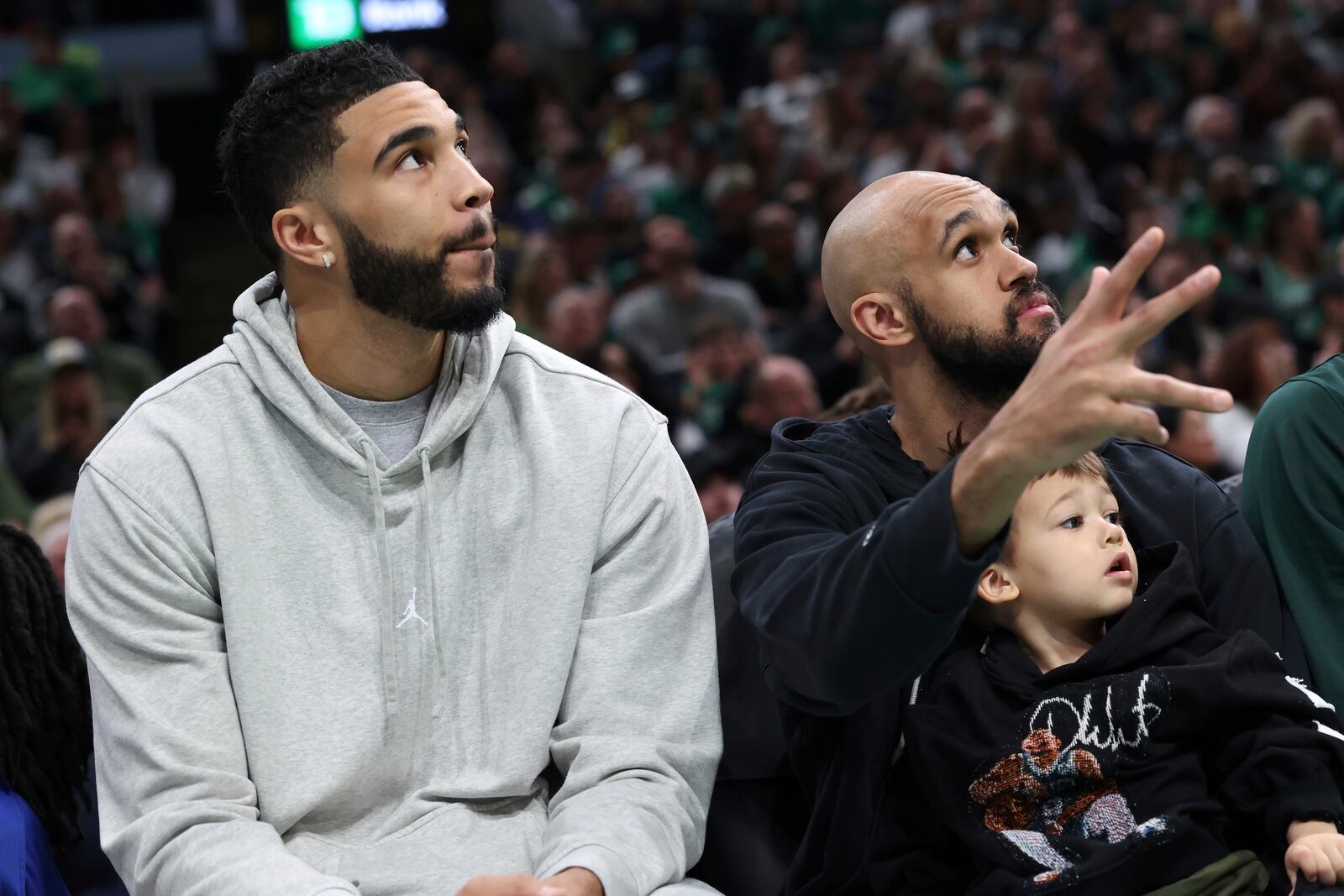 Boston Celtics' Jayson Tatum, left, and Derrick White watch from the bench during the first half of an NBA basketball game against the Charlotte Hornets Sunday, April 13, 2025, in Boston. (AP Photo/Michael Dwyer)