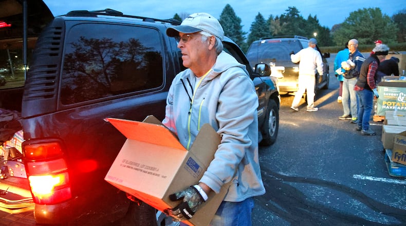 Brian Cox loads a car at the Second Harvest Food Bank food distribution at Clark State Monday, Nov. 6, 2023. BILL LACKEY/STAFF