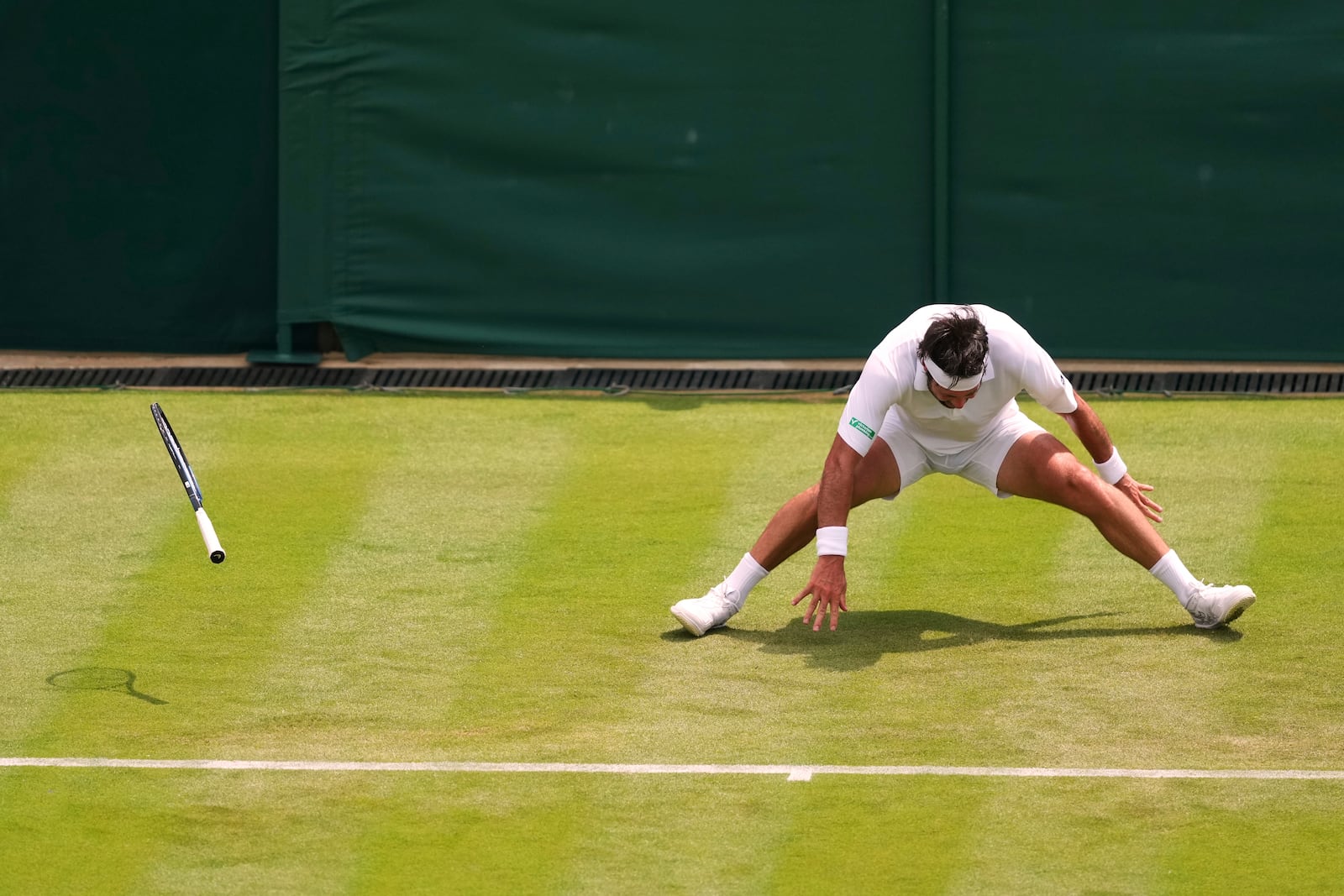 Nikoloz Basilashvili of Georgia falls during his first round men's singles match against Lorenzo Musetti of Italy at the Wimbledon Tennis Championships in London, Tuesday, July 1, 2025.(AP Photo/Joanna Chan)