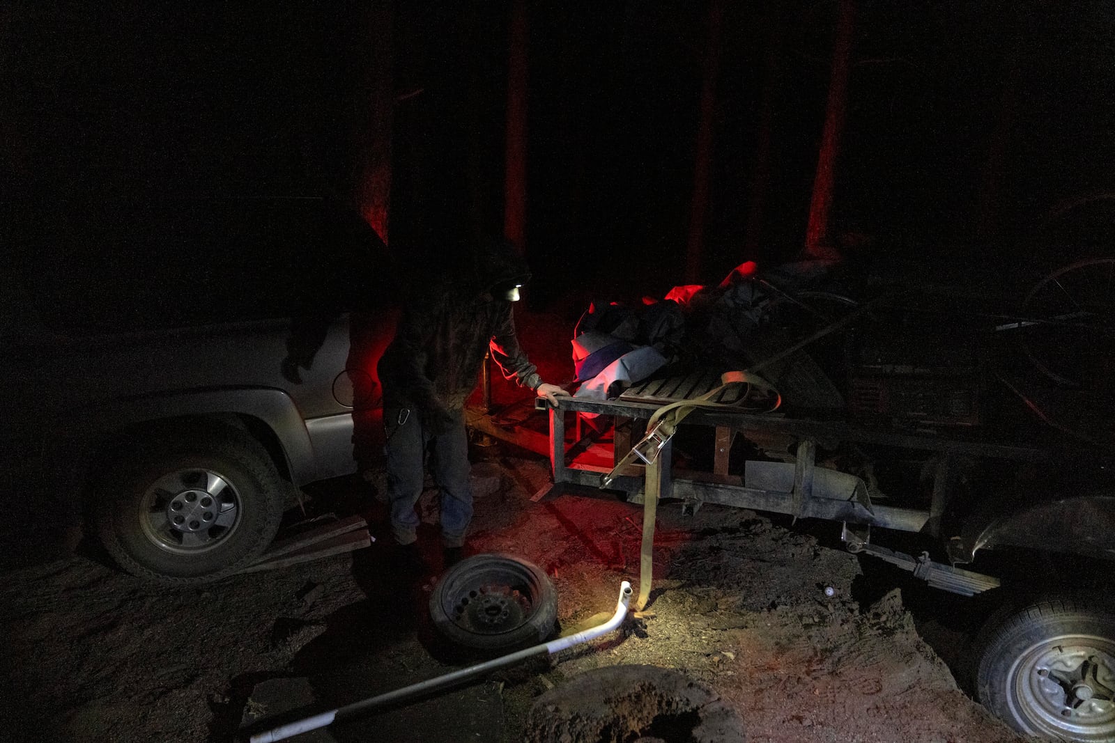 Mike Shelton works to attach a hitch to a vehicle as he loads up his belongings at a homeless encampment in Deschutes National Forest Wednesday, April 30, 2025 near Bend, Ore. (AP Photo/Jenny Kane)