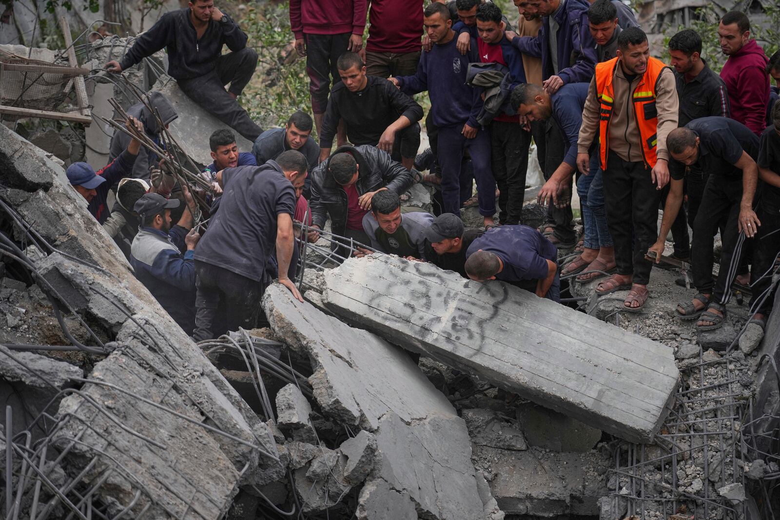 Volunteers and emergency workers try to move a concrete pillar as they search for bodies and survivors from the rubble of the Manoun family's house after it was targeted by an Israeli army strike in Jabalia al-Balad, Gaza City, Sunday, April 13, 2025. (AP Photo/Jehad Alshrafi)