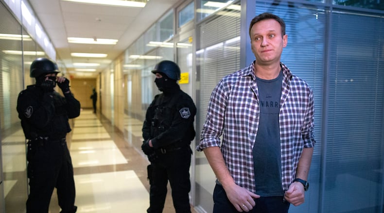 FILE - Russian opposition leader Alexei Navalny speaks to the media in front of security officers standing guard at the Foundation for Fighting Corruption office in Moscow, Russia, Thursday, Dec. 26, 2019. (AP Photo/Alexander Zemlianichenko, File)