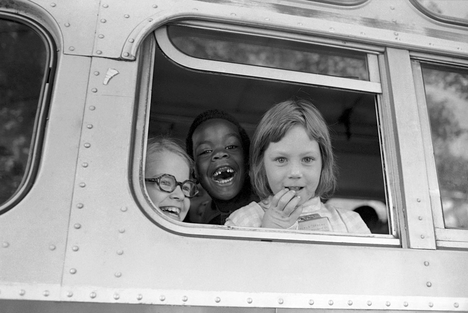 FILE - Children smile from window of a school bus in Springfield, Mass., as court-ordered busing brought Black children and white children together in elementary grades without incident, Sept. 16, 1974. (AP Photo/Peter Bregg, File)