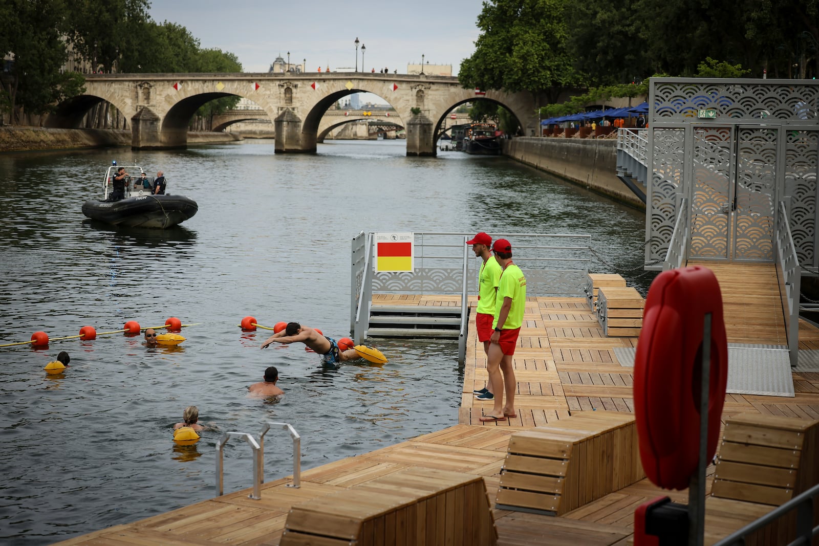 A swimmer dives in the water as people swim at the Pont Marie safe bathing site on the Seine river in Paris, France, Saturday, July 5, 2025, during the opening of the three Seine swimming pools, as part of the 'Paris Plages' event. (AP Photo/Thomas Padilla)