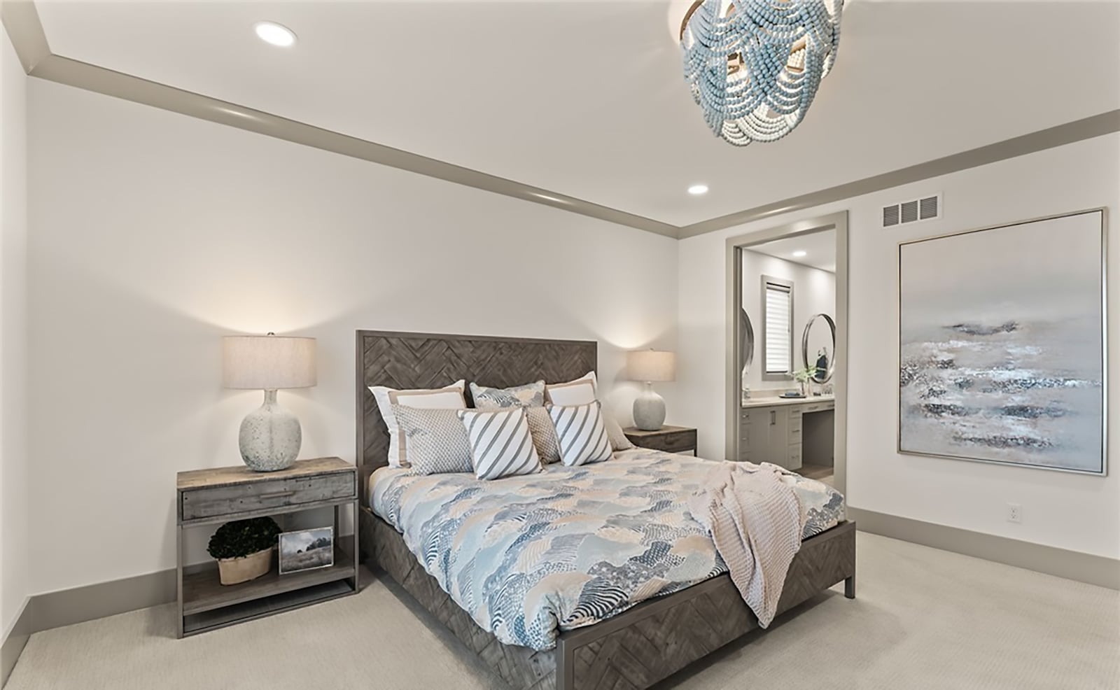 The primary bedroom suite has carpeting, a ceiling light, recessed lighting and crown molding. There is an ensuite bathroom with a zero entry walk in shower and a walk in closet with custom organizing system. CONTRIBUTED