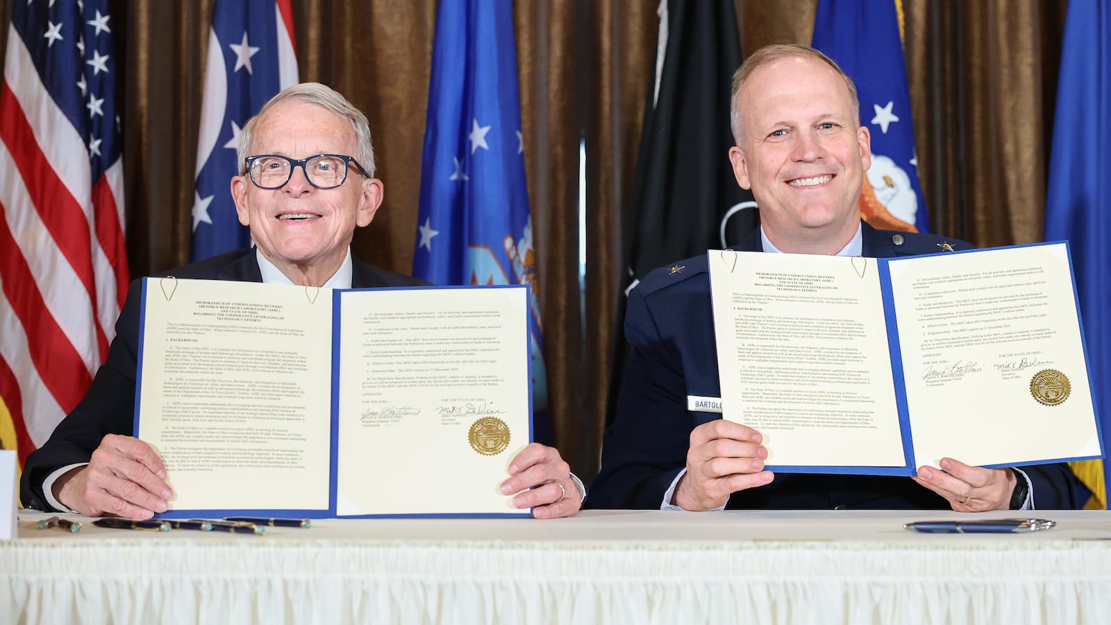 Gov. Mike DeWine (left) and Air Force Brig. Gen. Jason Bartolomei, commander of the Air Force Research Laboratory at Wright-Patterson Air Force Base, pose after signing copies of a memorandum of understanding between the State of Ohio and AFRL on Monday at Pentagon Tower in Beavercreek. The memorandum renews a partnership between the two entities to share science and technology information and foster economic developing within Ohio. BRYANT BILLING / STAFF