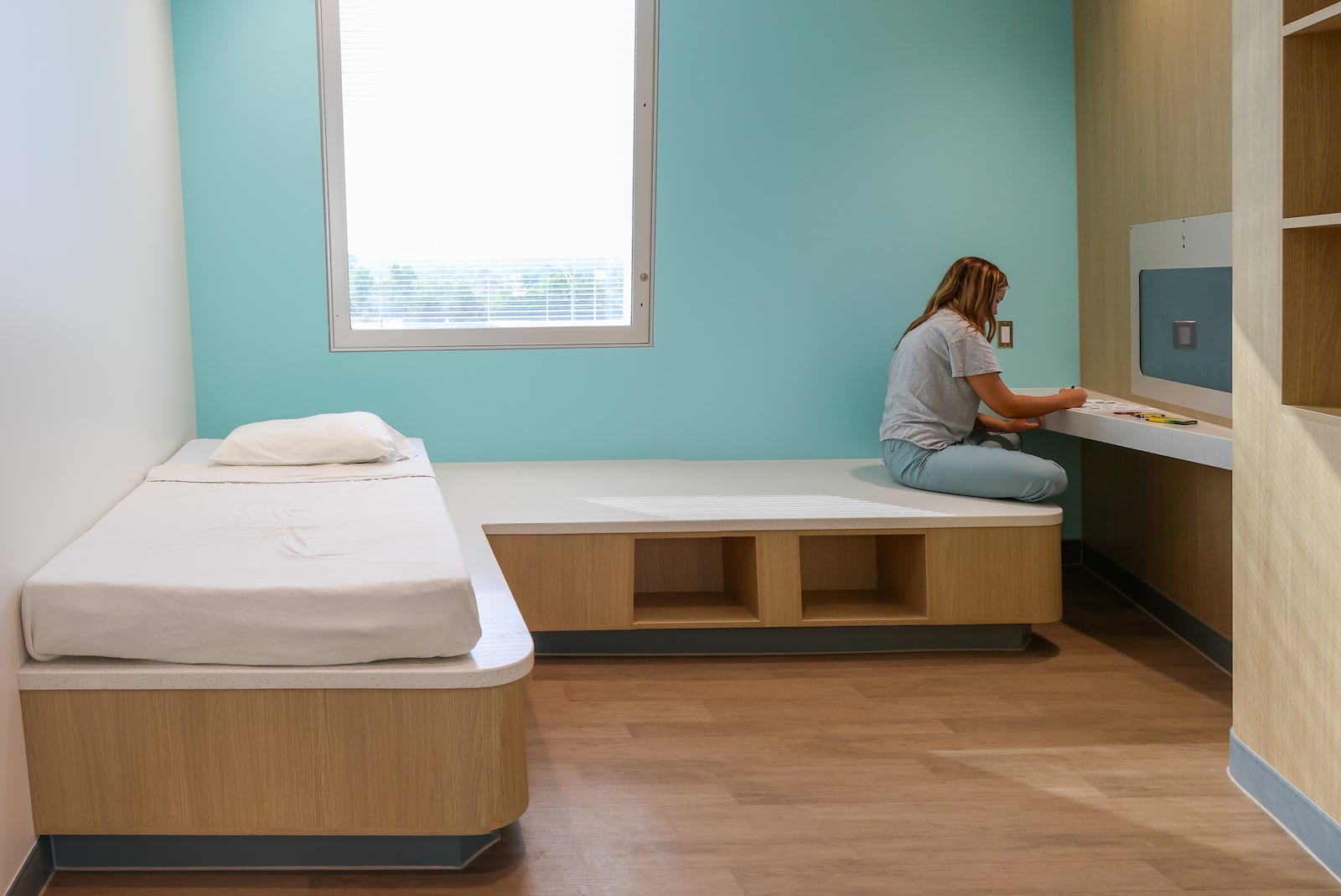 Eleanor Hake, an intern for Dayton Children's, colors while posing as a patient to demonstrate functionality in a room at Dayton Children's Mathile Center for Mental Health and Wellness. The center started serving patients in July. BRYANT BILLING / STAFF