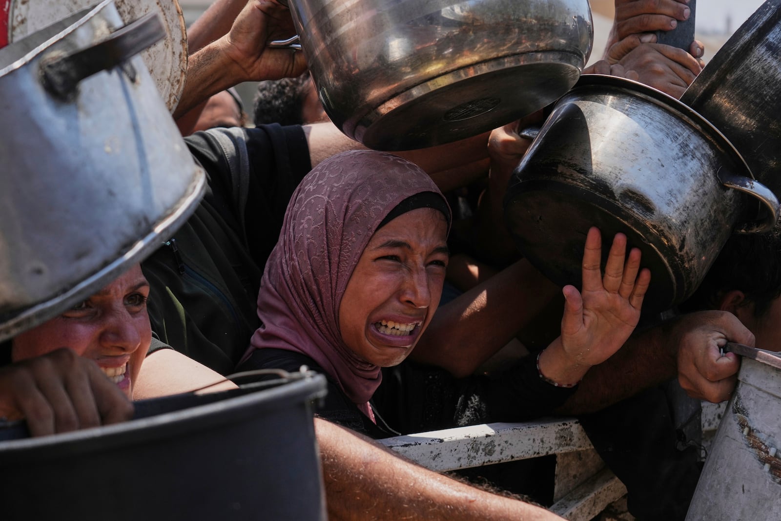 Palestinians struggle to get donated food at a community kitchen, in Gaza City, northern Gaza Strip, Saturday, July 26, 2025. (AP Photo/Abdel Kareem Hana)