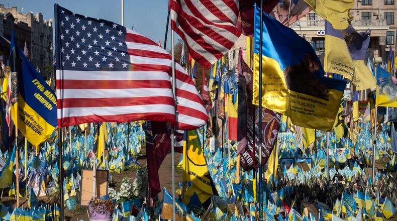 FILE - US and Ukrainian national flags wave to commemorate American volunteers, who were killed in battles with Russian troops defending Ukraine, their names are on flags, at the improvised war memorial in Independence square in Kyiv, Ukraine, Sept. 27, 2024. (AP Photo/Efrem Lukatsky, File)