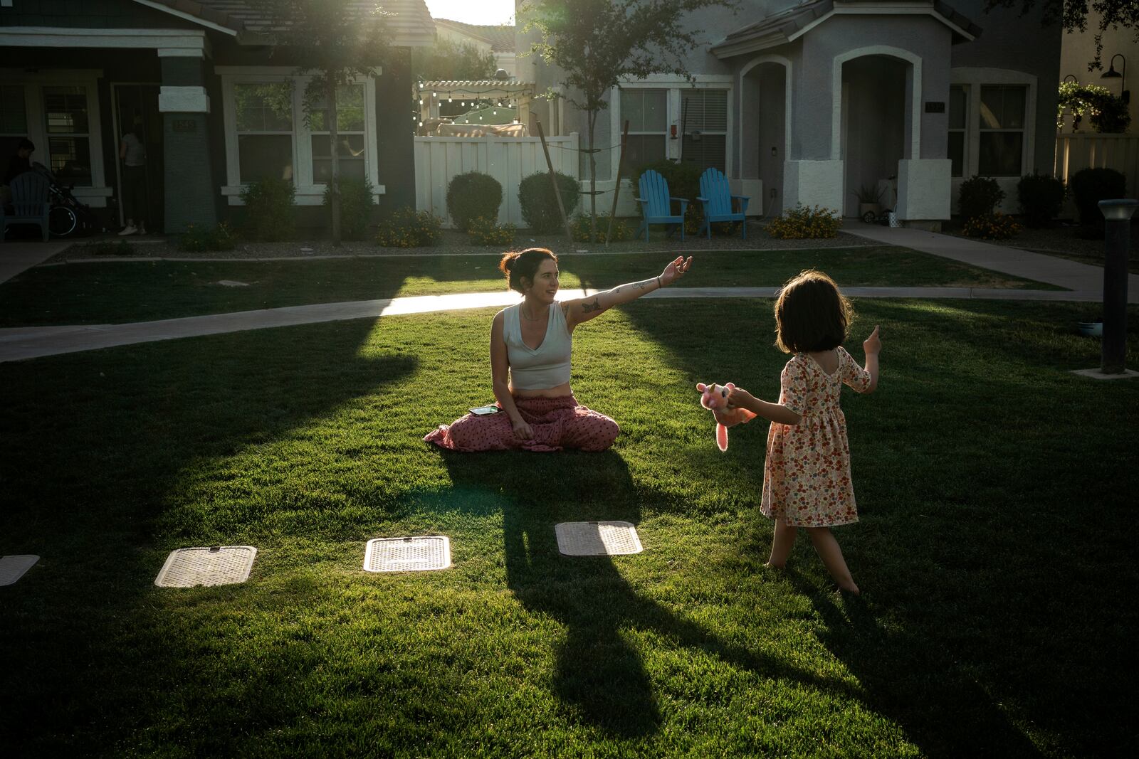 Maria Padron, center, plays with her daughter Fae Padron, 4, right, in a "kid pod," a cluster of families with more than 20 kids between them, at Agritopia, a community nestled around a plot of agricultural land, April 21, 2025, in Gilbert, Ariz. (AP Photo/Annika Hammerschlag)