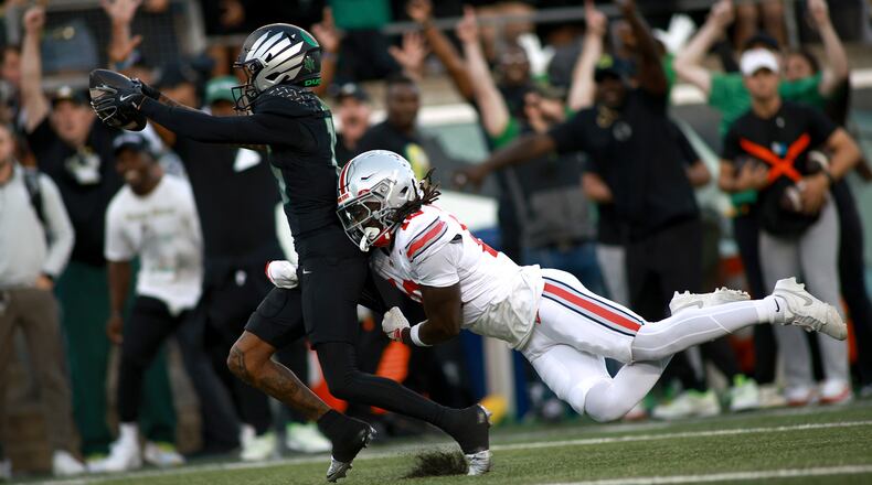 Oregon wide receiver Tez Johnson, left, escapes a tackle by Ohio State cornerback Denzel Burke, right, for a touchdown during an NCAA college football game, Saturday, Oct. 12, 2024, in Eugene, Ore. (AP Photo/Lydia Ely)