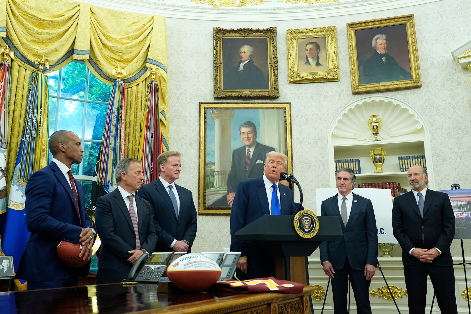 President Donald Trump, third from right, speaks as Commerce Secretary Howard Lutnick, from right, Interior Secretary Doug Burgum, and from left, Secretary of Housing and Urban Development Scott Turner, Washington Commanders owner Josh Harris and NFL Commissioner Roger Goodell listen during an event to announce that the 2027 NFL Draft will be held on the National Mall, in the Oval Office of the White House, Monday, May 5, 2025, in Washington. (AP Photo/Alex Brandon)