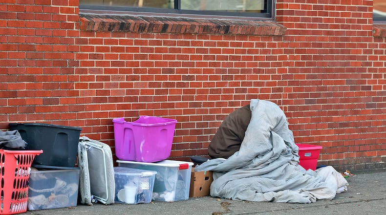 A person tries hide from the morning chill under a blanket Thursday, Nov. 7, 2024 along West Main Street in Springfield. BILL LACKEY/FILE