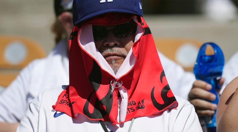 A Los Angeles Dodgers fan covers up from the hot sun during the second inning of a spring training baseball game against the Athletics, Saturday, March 21, 2026, in Phoenix. (AP Photo/Ross D. Franklin)