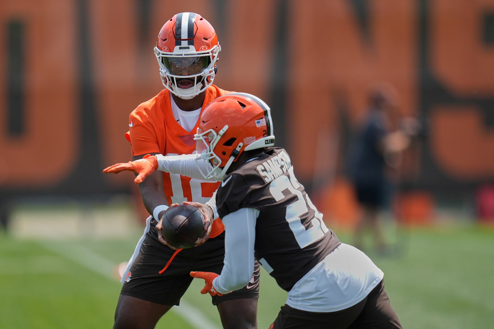 Cleveland Browns quarterback Shedeur Sanders (12) hands off to running back Dylan Sampson (22) during NFL football practice in Berea, Ohio, Wednesday, June 4, 2025. (AP Photo/Sue Ogrocki)