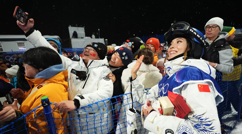China's Eileen Gu takes photos with attendees after the women's freestyle skiing halfpipe qualifications at the 2026 Winter Olympics, in Livigno, Italy, Thursday, Feb. 19, 2026. (AP Photo/Lindsey Wasson)