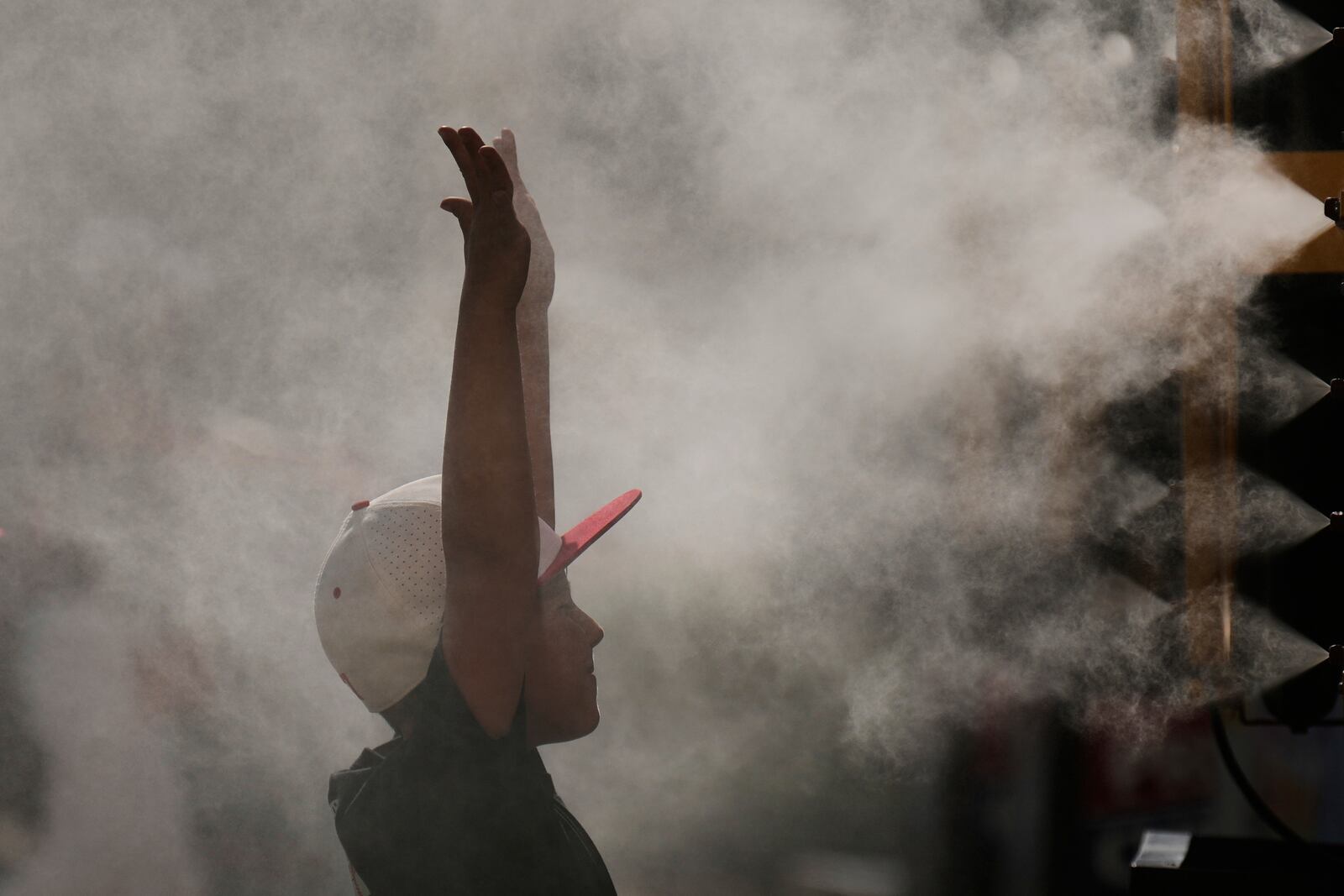 A boy cools off in a mister at Kauffman Stadium before a baseball game between the Kansas City Royals and the Tampa Bay Rays, Wednesday, June 25, 2025, in Kansas City, Mo. (AP Photo/Charlie Riedel)