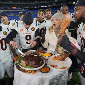 Cincinnati Bengals quarterback Joe Burrow (9) joined by NBC Sports sideline reporter Melissa Stark, right, carves a turkey after NFL football game against the Baltimore Ravens, Thursday, Nov. 27, 2025, in Baltimore. (AP Photo/Stephanie Scarbrough)