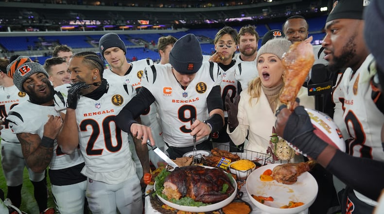 Cincinnati Bengals quarterback Joe Burrow (9) joined by NBC Sports sideline reporter Melissa Stark, right, carves a turkey after NFL football game against the Baltimore Ravens, Thursday, Nov. 27, 2025, in Baltimore. (AP Photo/Stephanie Scarbrough)
