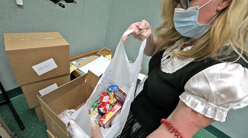 Sonya Knisley, head of children's services at the Clark County Library, takes a meal bag out of a box Thursday at the main library. BILL LACKEY/STAFF