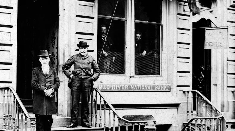In 1846 that Mad River Valley Bank of Ohio opened as the first bank in Springfield with a capital of $100,000. It was incorporated as the Mad River National Bank in January 1865 and in 1869, the building shown here at 22 E. Main Street was constructed. Employees of the bank are shown here in the last 1870s: Thomas McGrew (left) and Charles Bacon (later president and vice president) with C.F. Harrison and Joe Sharp looking out of the windows. The Mad River Bank merged with the First National Bank of Springfield in 1928 and moved to what is today known as Hull Plaza at the northwest corner of Main and Fountain. PHOTO COURTESY OF THE CLARK COUNTY HISTORICAL SOCIETY
