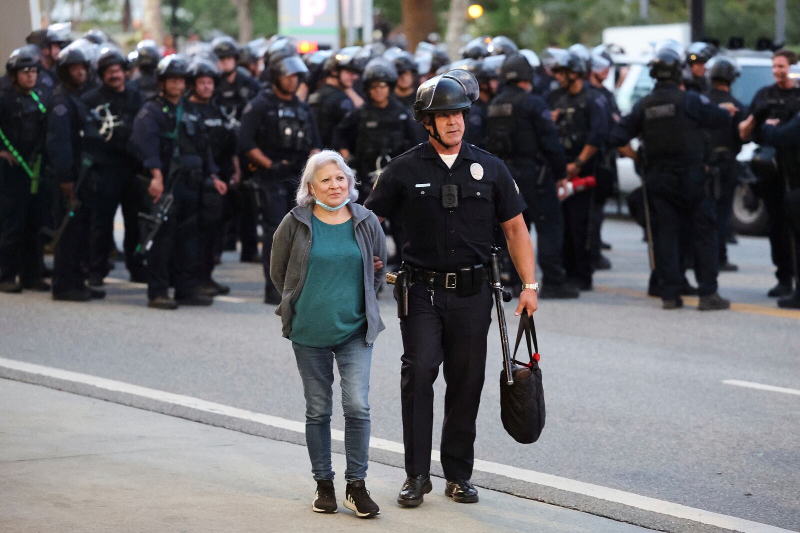 A law enforcement officer escorts a woman out of a protest after she was detained on Wednesday, June 11, 2025, in Los Angeles. (AP Photo/Ethan Swope)