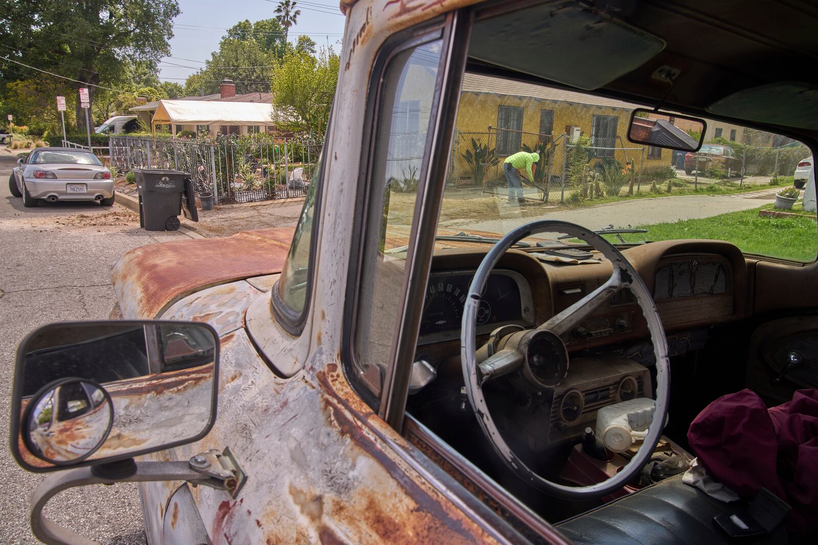 An immigrant gardener clears the dirt of the front lawn of a home located within the Eaton Fire damaged area in Altadena, Calif., on Friday, April 4, 2025. (AP Photo/Damian Dovarganes)