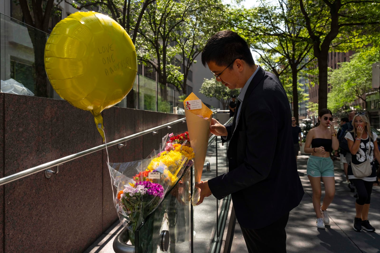 A person leaves flowers at a make shift memorial outside scene of Monday's deadly shooting, Tuesday, July 29, 2025, in New York. (AP Photo/Yuki Iwamura)