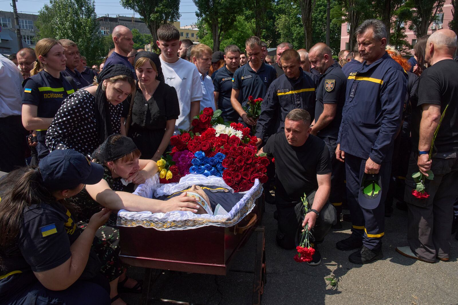 Colleagues and relatives say the last goodbye to firefighters Pavlo Yezhor, Danylo Skadin and Andriy Remenny, killed by Russia's missile attack last week, at the farewell ceremony in front of the fire station in Kyiv, Ukraine, Monday, June 9, 2025. (AP Photo/Efrem Lukatsky)