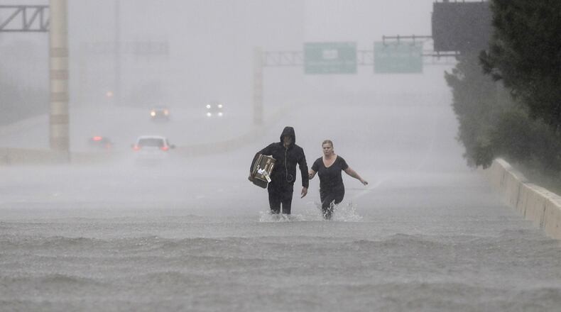 Two people walk down a flooded section of Interstate 610 in floodwaters from Tropical Storm Harvey on Sunday, Aug. 27, 2017, in Houston, Texas. (AP Photo/David J. Phillip)